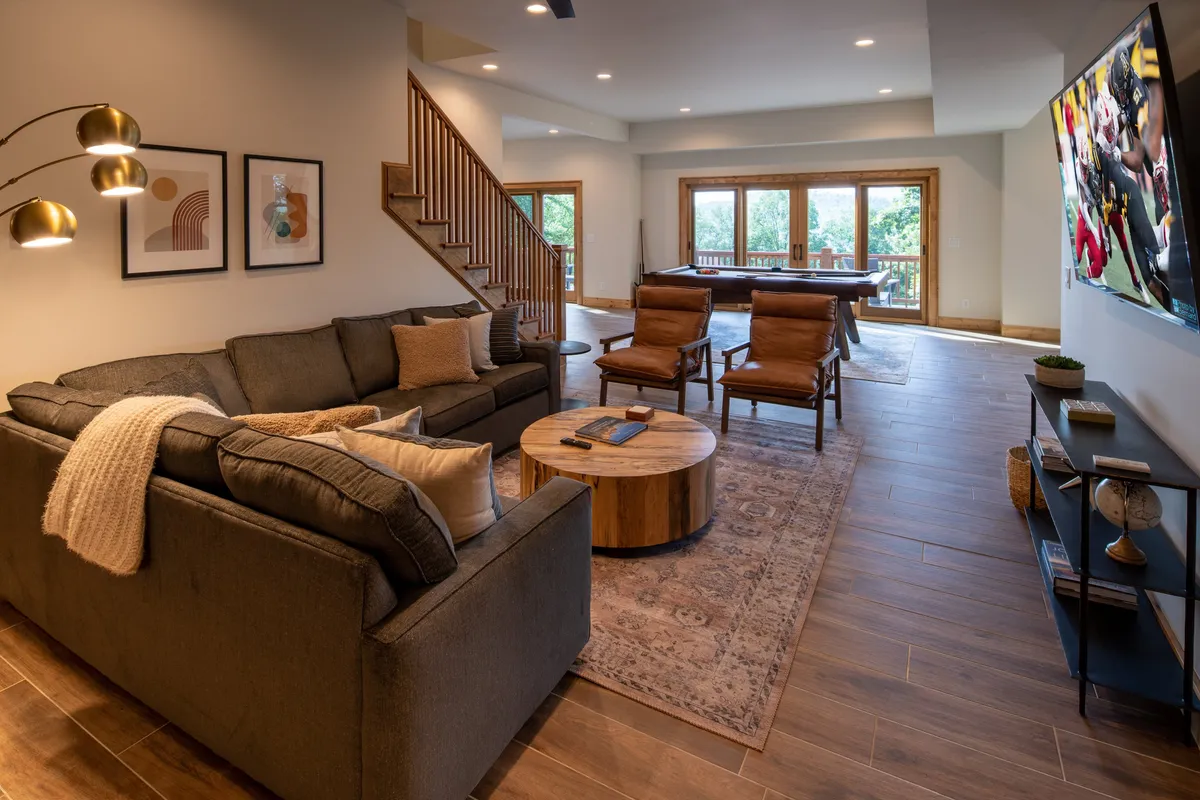 A cozy multi-use living space with a sofa, coffee table, television, and artwork on the walls. The presence of a TV and comfortable seating highlights the entertainment options, while the visible layout suggests a versatile area for game nights, movie watching, or relaxing after a workout.