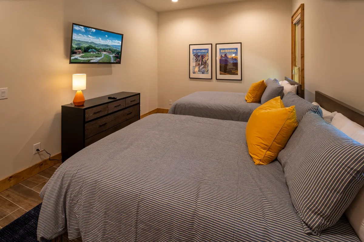 A comfortable bedroom with beds, a television, and artwork, suggesting a restful retreat after an active day. The image conveys the idea of recharging before another round of outdoor fun.